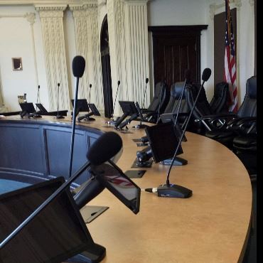 City commission chamber dais with microphones and mounted iPads