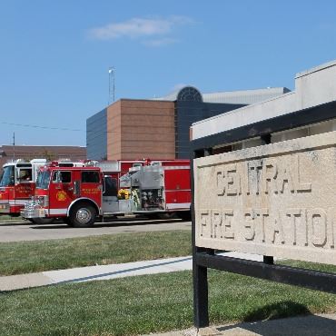 City fire station with two red fire vehicles in the driveway.