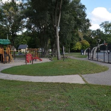 Park with playground on left, basketball court on right, and sidewalk connecting