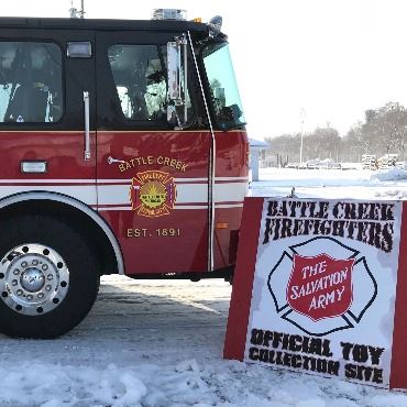 Battle Creek fire engine parked by a toy donation sign.