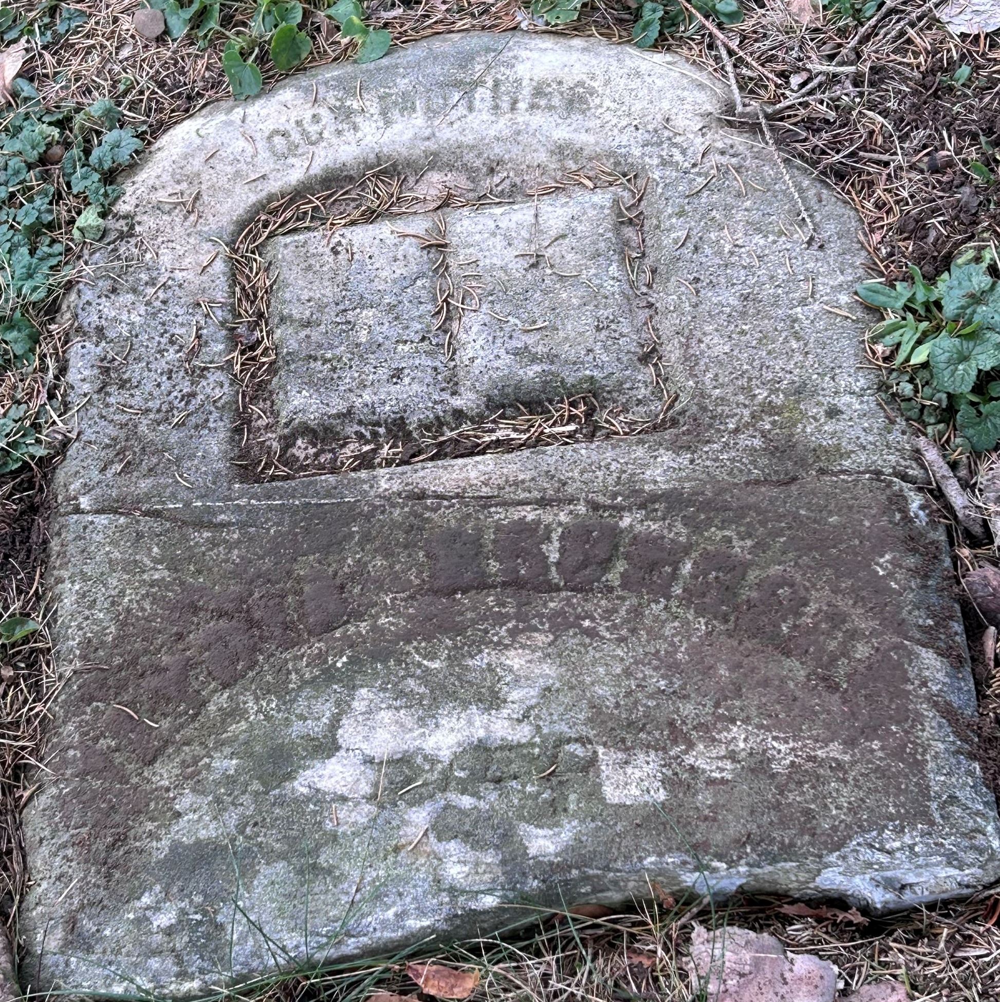 Photo of broken and buried headstone - staff unable to read deceased's name