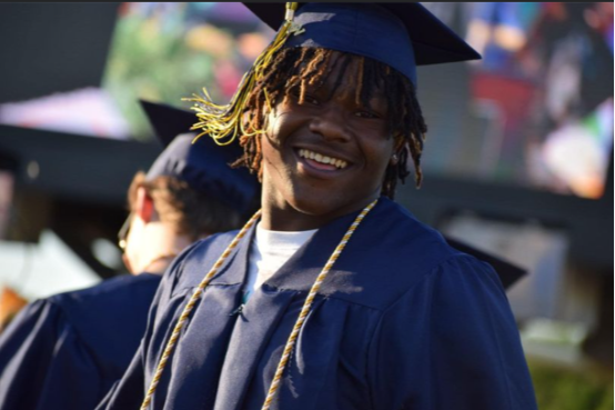 Young black man wearing navy blue graduation robe and cap