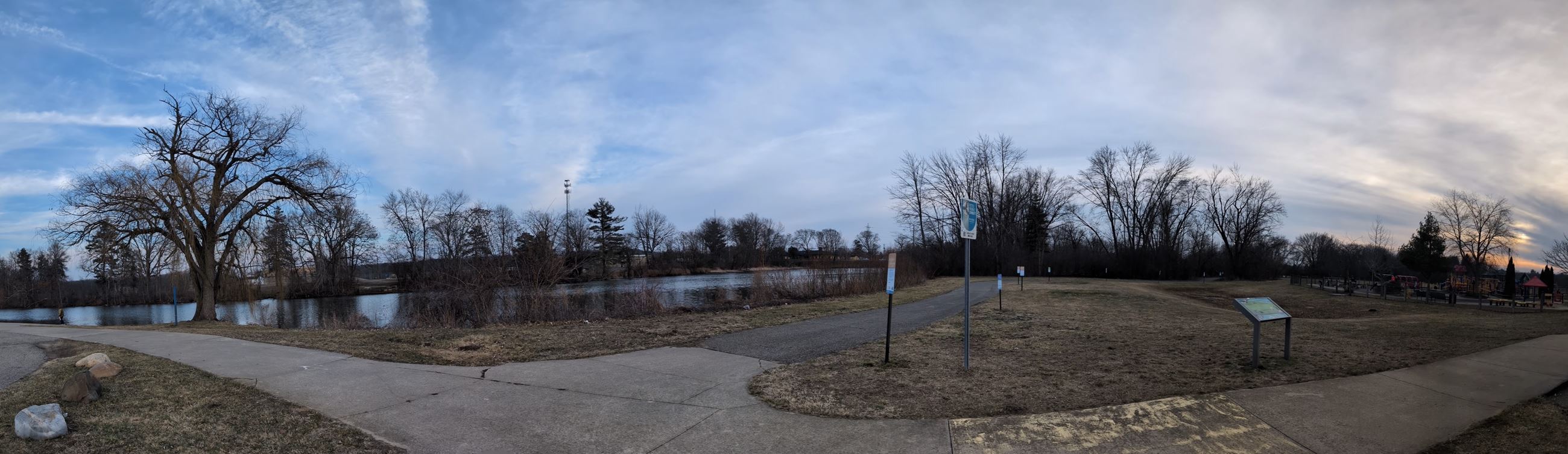Panorama showing river, boat launch, multi-use path, and playground.
